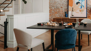 Lifestyle image of beige and petrol Mobitec Cuori chairs at a black table by a brick wall