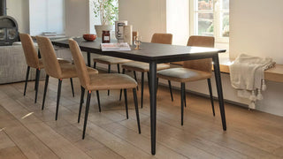 Lifestyle image of cognac Mobitec Rob chairs with black legs at a wooden table
