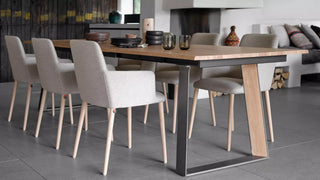 Lifestyle image of cream Mobitec Rob armchairs around a long wooden table in a loft