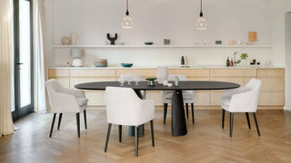 Sfeerbeeld van witte Mobitec Saga draaistoelen aan een ovale zwarte tafel in een lichte eetkamer
