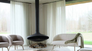 Sfeerbeeld van grijze Mobitec Thalia fauteuils en bankje rond een hangende haard