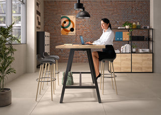 Lifestyle image of a Buronomic Alto bookcase in black and Nebraska behind a woman at a high table