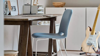 Photo d'ambiance d'une chaise Mobitec Pamp bleue à une table en bois avec guitare