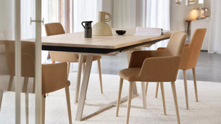 Lifestyle image of cognac Mobitec Rob armchairs at a wooden table in a bright dining room