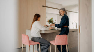 Lifestyle image of two women on pink Mobitec Rob bar stools at a kitchen island