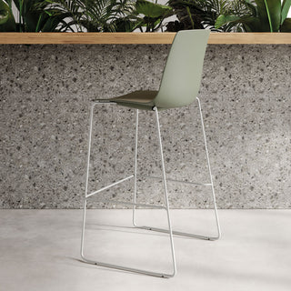 Sfeerbeeld van een saliegroene Frezza YO Plastic barkruk aan een terrazzo bar